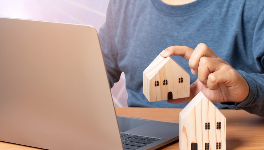 un homme tenant une maison en bois